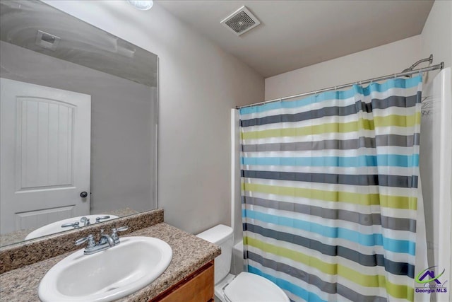 bathroom featuring toilet, vanity, and curtained shower