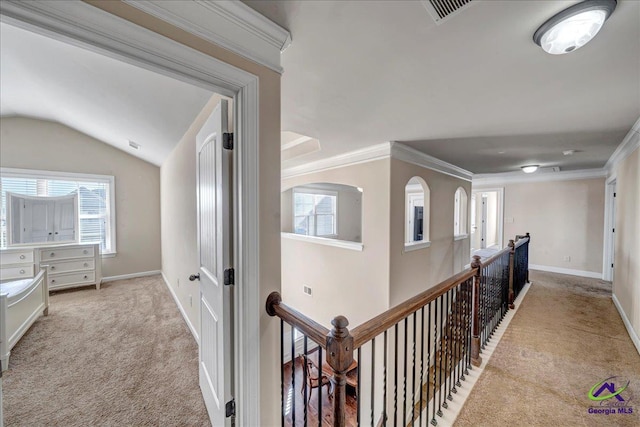 hallway with vaulted ceiling, ornamental molding, and light colored carpet