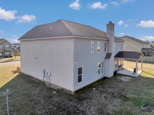 back of house with a lawn and a patio