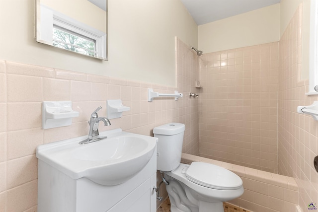 bathroom featuring tile walls, tiled shower, vanity, and toilet