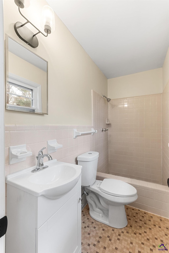 bathroom with tile walls, toilet, vanity, and tile patterned flooring