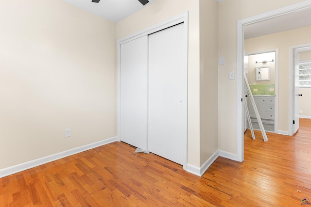 unfurnished bedroom with ceiling fan, a closet, and light hardwood / wood-style floors