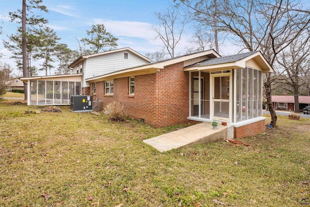 back of property with a sunroom, cooling unit, and a lawn