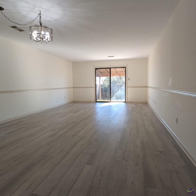 empty room with dark hardwood / wood-style flooring and an inviting chandelier