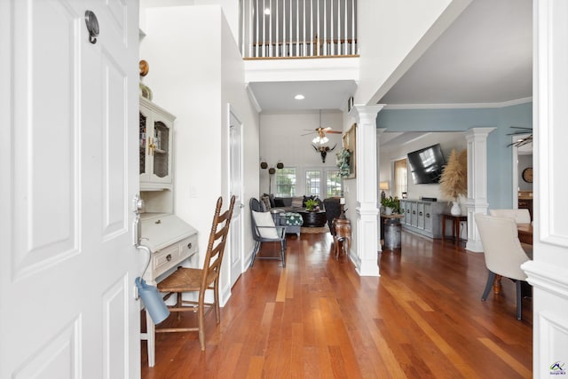 entryway with hardwood / wood-style floors, a towering ceiling, ornate columns, ceiling fan, and crown molding