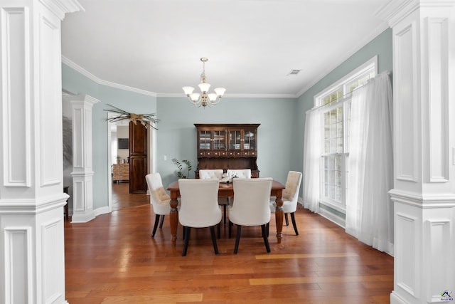 dining space with crown molding, decorative columns, a chandelier, and dark hardwood / wood-style floors