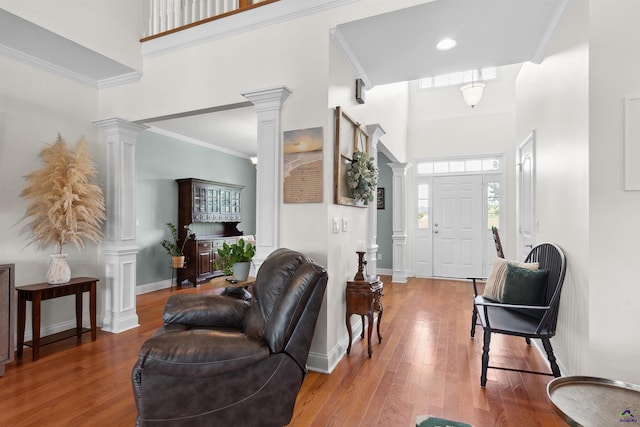 foyer featuring decorative columns, a high ceiling, and hardwood / wood-style floors