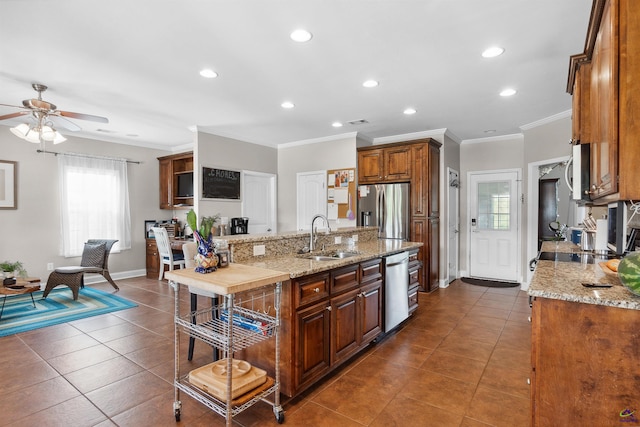 kitchen with crown molding, dark tile patterned flooring, sink, stainless steel appliances, and light stone counters