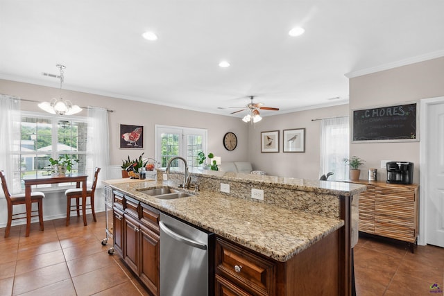 kitchen featuring stainless steel dishwasher, sink, decorative light fixtures, a wealth of natural light, and an island with sink