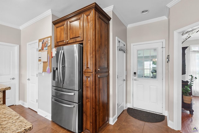 kitchen with light stone counters, crown molding, dark tile patterned flooring, and stainless steel fridge