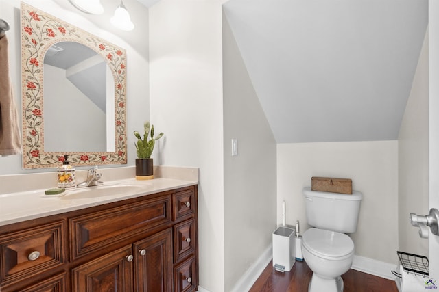 bathroom with wood-type flooring, toilet, vaulted ceiling, and vanity