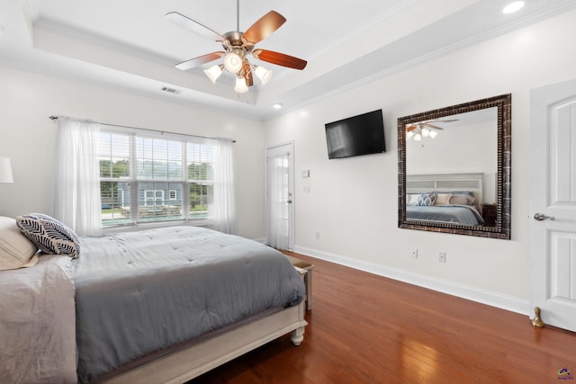 bedroom with ceiling fan, dark wood-type flooring, a tray ceiling, and ornamental molding