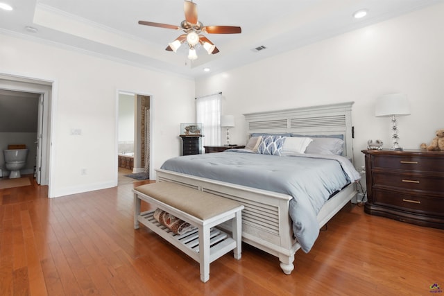 bedroom featuring hardwood / wood-style floors, ornamental molding, a raised ceiling, ceiling fan, and ensuite bathroom