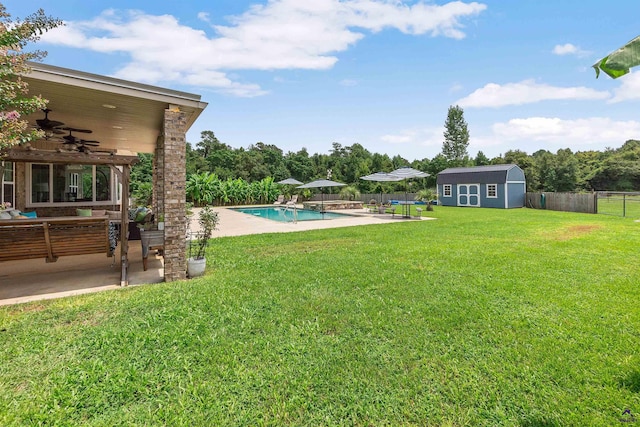 view of yard featuring ceiling fan, a fenced in pool, a patio, and a storage unit