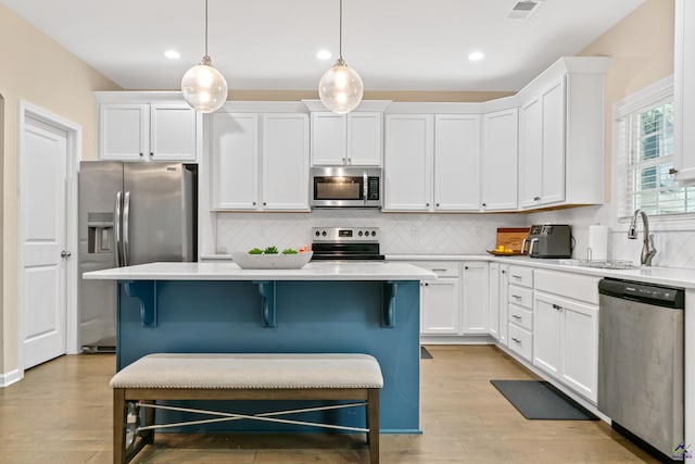 kitchen featuring white cabinetry, hanging light fixtures, and appliances with stainless steel finishes