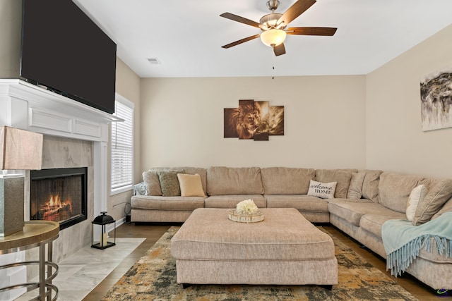 living room with wood-type flooring, a tile fireplace, and ceiling fan