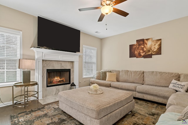 living room featuring ceiling fan, a high end fireplace, and dark wood-type flooring