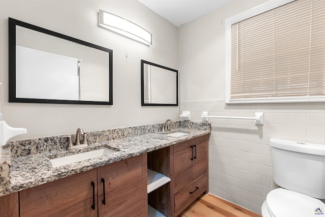 bathroom featuring hardwood / wood-style floors, toilet, vanity, and tile walls