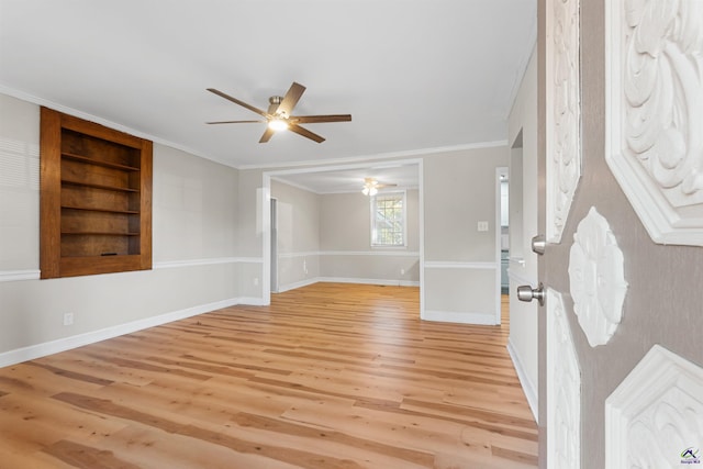 unfurnished room with built in shelves, light hardwood / wood-style floors, ceiling fan, and ornamental molding