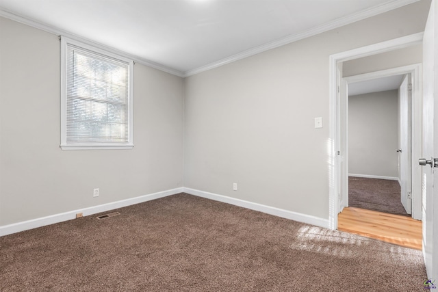 empty room with ornamental molding and carpet flooring