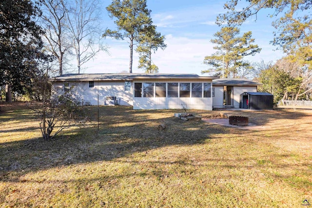 view of front of home with a front yard, a storage shed, and a fire pit