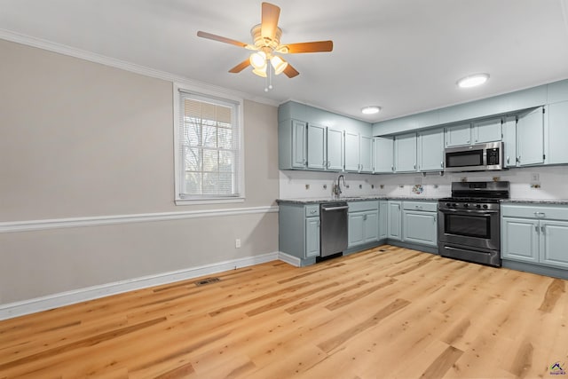 kitchen featuring sink, gray cabinets, ornamental molding, light hardwood / wood-style floors, and stainless steel appliances