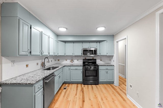 kitchen featuring light stone countertops, stainless steel appliances, sink, light hardwood / wood-style flooring, and crown molding