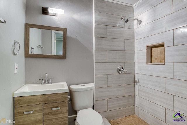 bathroom with vanity, toilet, and tiled shower