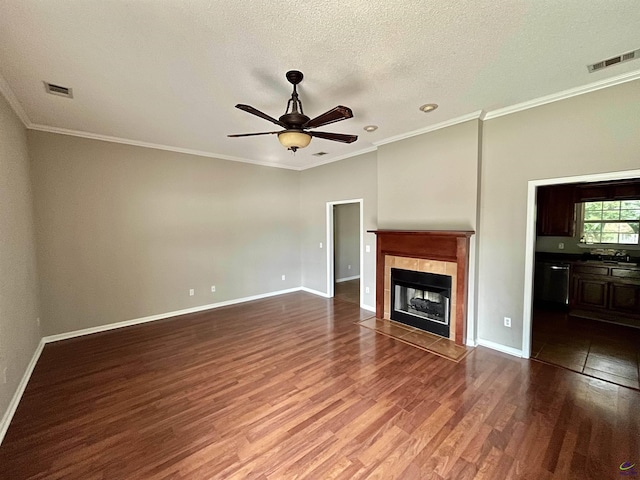 unfurnished living room with a textured ceiling, wood-type flooring, ceiling fan, crown molding, and a tiled fireplace