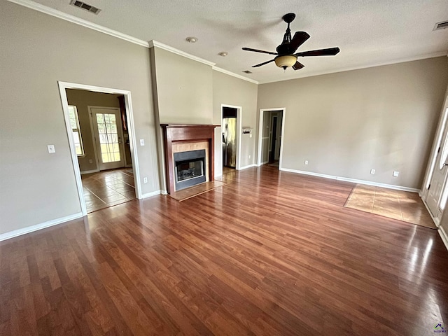 unfurnished living room featuring dark wood-type flooring, a textured ceiling, ceiling fan, and ornamental molding