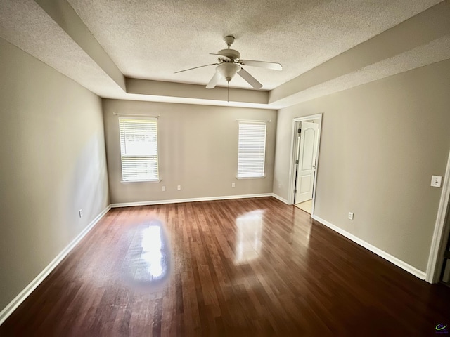 spare room with wood-type flooring, a textured ceiling, a tray ceiling, and ceiling fan