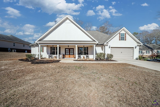 view of front of home featuring a porch, a garage, and a front lawn