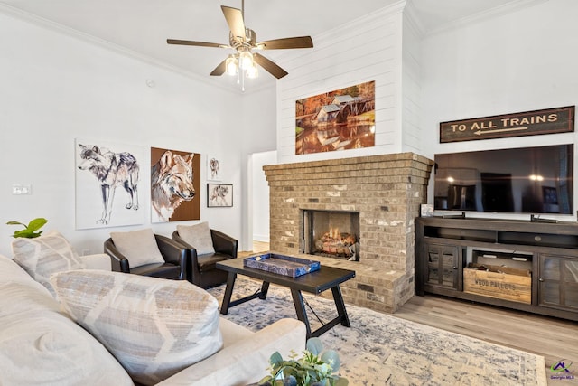 living room featuring crown molding, ceiling fan, a fireplace, and light hardwood / wood-style floors