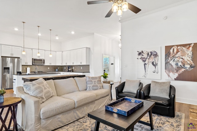 living room with ceiling fan, ornamental molding, and light hardwood / wood-style floors