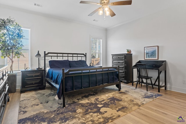 bedroom featuring wood-type flooring, ornamental molding, and ceiling fan