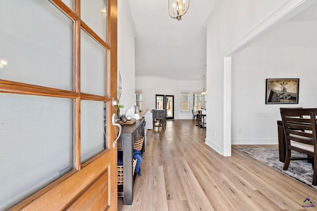 foyer entrance with an inviting chandelier, light hardwood / wood-style flooring, and a high ceiling