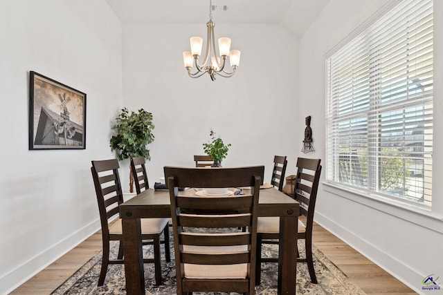 dining area featuring an inviting chandelier, wood-type flooring, and vaulted ceiling