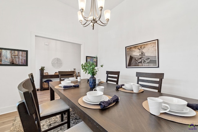 dining room with a notable chandelier, light hardwood / wood-style flooring, and a high ceiling