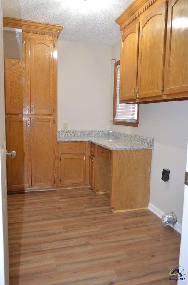 kitchen with light stone counters, a textured ceiling, and light hardwood / wood-style flooring