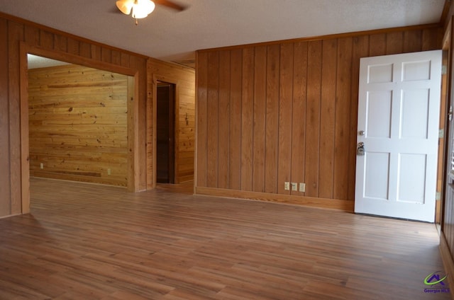 unfurnished room featuring wood-type flooring, wooden walls, and a textured ceiling