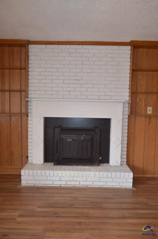 room details with hardwood / wood-style flooring, a brick fireplace, and a textured ceiling