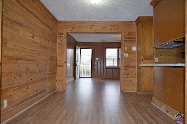 kitchen with wood-type flooring, a textured ceiling, and wood walls