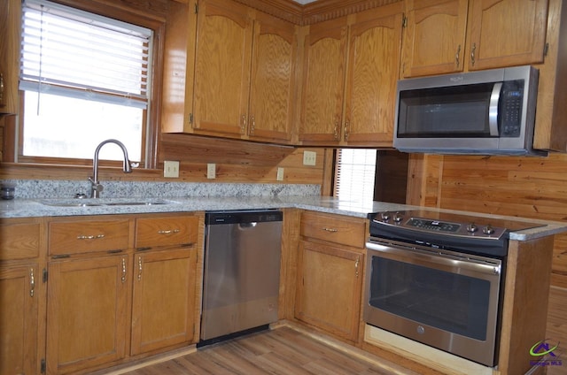 kitchen featuring light stone counters, appliances with stainless steel finishes, light hardwood / wood-style floors, and sink