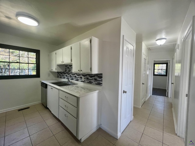 kitchen with sink, light tile patterned floors, dishwasher, white cabinets, and backsplash