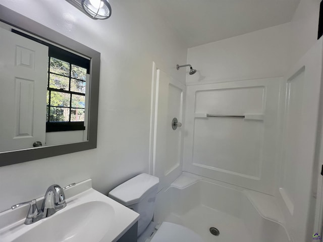 bathroom with vanity, toilet, and a shower