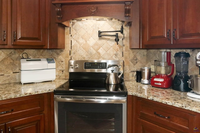 kitchen featuring electric stove, tasteful backsplash, light stone counters, and custom exhaust hood