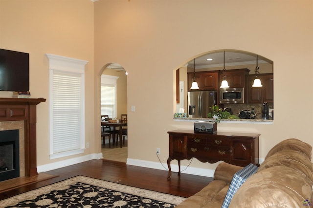 living room with a premium fireplace, crown molding, and dark hardwood / wood-style flooring