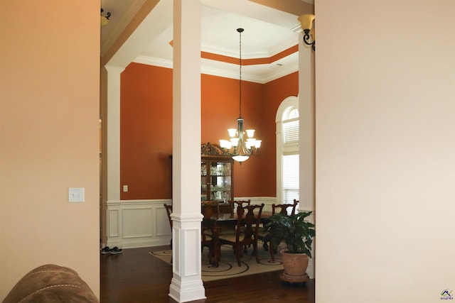 dining room with decorative columns, a notable chandelier, a tray ceiling, ornamental molding, and dark hardwood / wood-style flooring