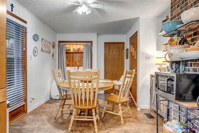 dining area featuring ceiling fan and a textured ceiling