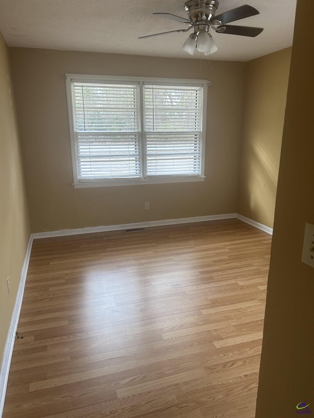 empty room with ceiling fan, a textured ceiling, and light hardwood / wood-style floors